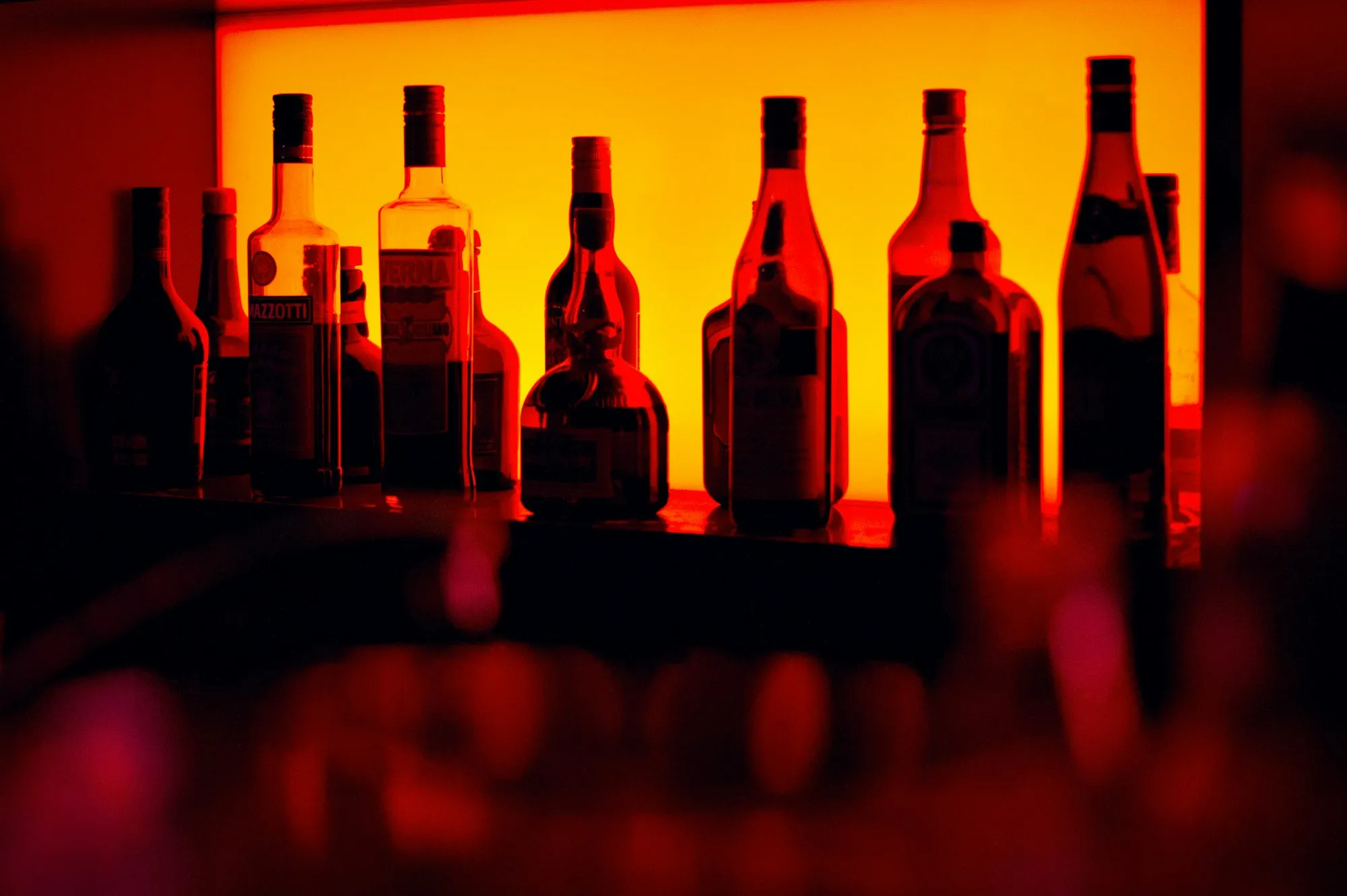 Bouteilles alignées en contre-jour sur une étagère illuminée